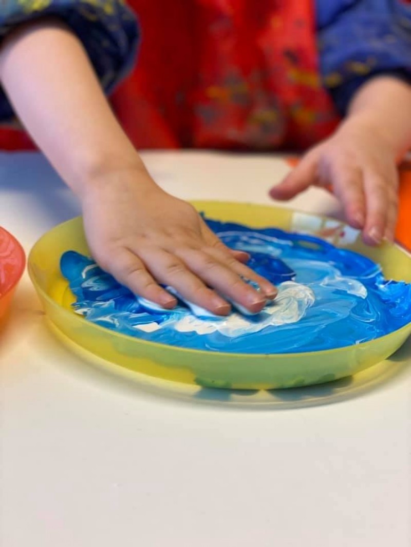 Barnehånd som dyppes i maling